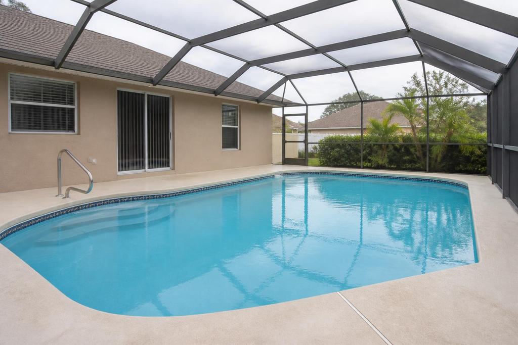 Typical Central Florida residential pool under a screened enclosure with a paved deck and clear blue water